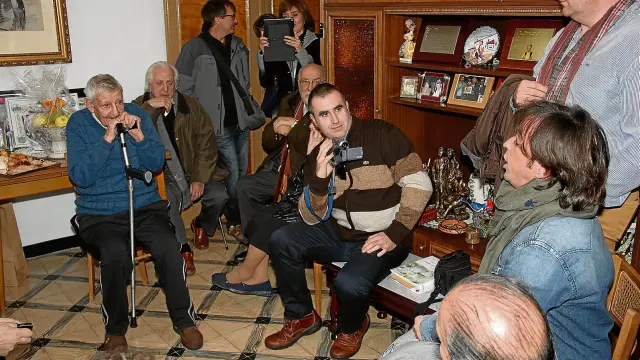 José Iranzo, a la izquierda, escucha atentamente en el salón de su casa al cantador Nacho del Río dedicándole una jota.