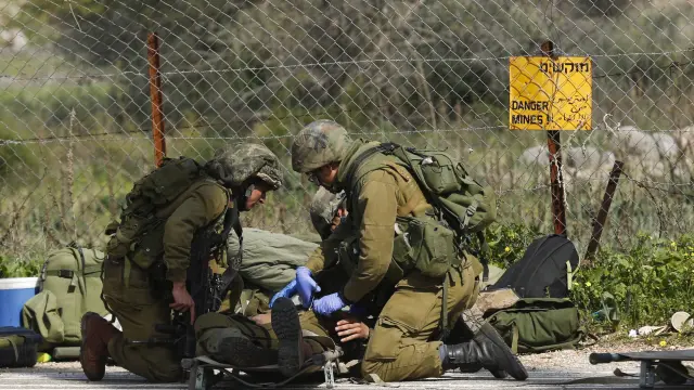 Un soldado isrelí herido recibe atención médica de varios compañeros después de que impactara un misil antitanques en su vehículo