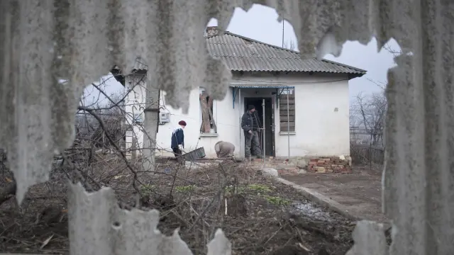 Unos ciudadanos ucranianos aprovechan el alto el fuego para reparar daños en su casa