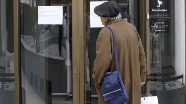 Un cliente lee un cartel ante la sucursal cerrada de Banco Madrid
