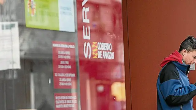 Un ciudadano consulta su móvil junto a una oficina de empleo del Inaem, en Aragón.