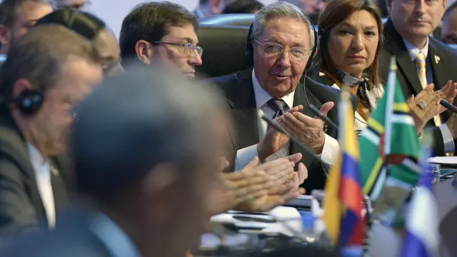 Obama en primer plano, desenfocado, con Raúl Castro aplaudiendo detrás