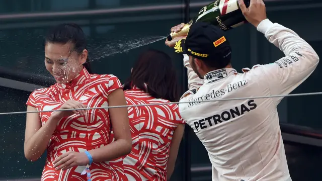 Hamilton celebra su victoria arrojando champán sobre una azafata.