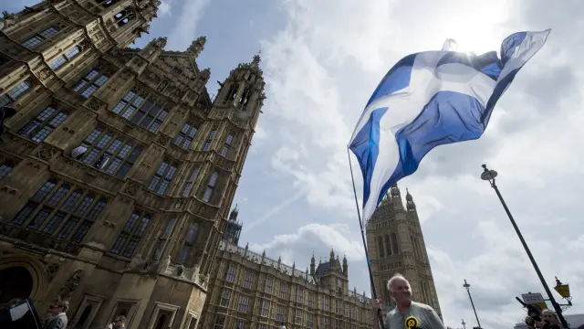 Un seguidor del Partido Nacionalista Escocés (SNP) ondea una bandera junto a la Cámara de los Comunes de Londres.