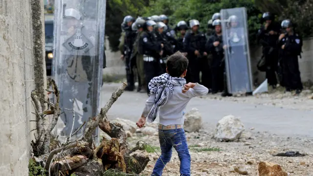 Un niño palestino lanza una piedra a soldados israelíes