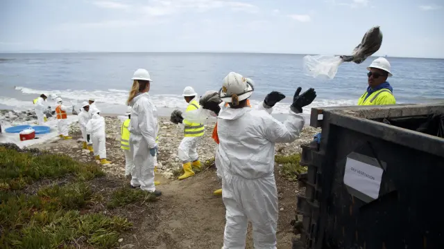 Varios trabajadores forman una cadena humana para limpiar la playa de petróleo en Santa Bárbara, California.