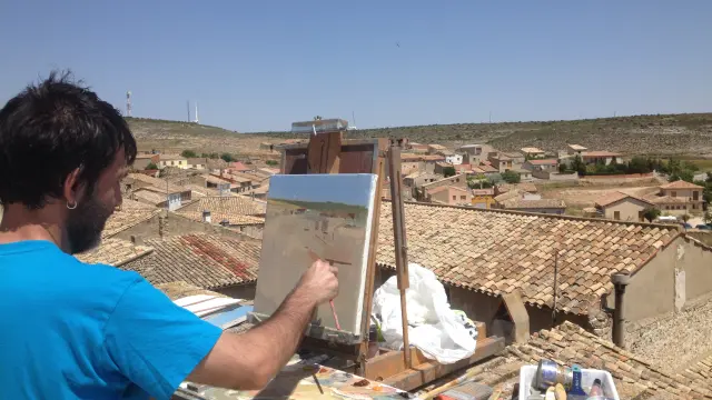Uno de los paisajistas invitado pinta en su caballete una panorámica del pueblo