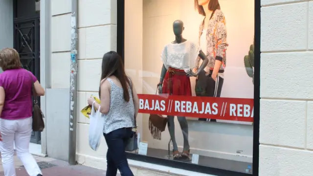Una joven pasea junto al escaparate de un establecimiento con rebajas en Zaragoza.