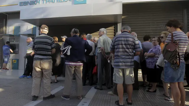 Varios griegos hacen cola para sacar dinero en un cajero en Atenas.