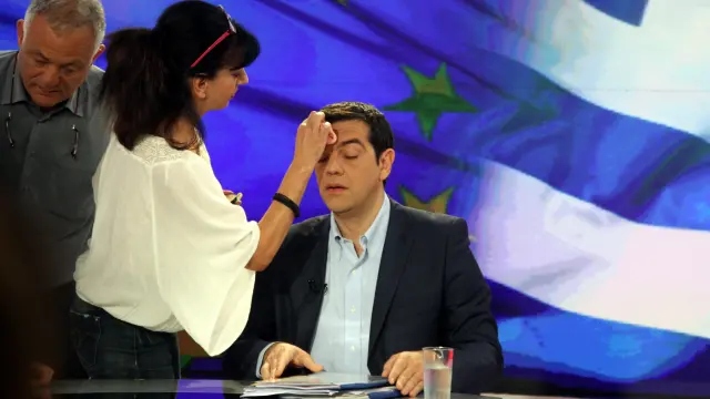 Una empleada de la televisión pública griega maquilla a Tsipras antes de la entrevista de la noche del lunes.