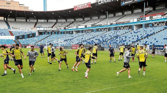 Los jugadores del Real Zaragoza, ayer, al inicio del entrenamiento a puerta cerrada en La Romareda.