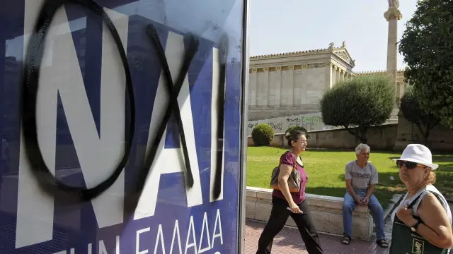 Una griega observa un cartel que pone 'no' sobre otro que defiende el 'sí' al referéndum del domingo.