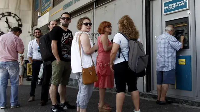 Atenienses hacen cola para retirar dinero en una sucursal del Banco Nacional de Grecia.