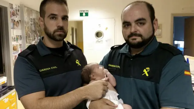 Los dos agentes de la Guardia Civil que encontraron al recién nacido, con el bebé en brazos.