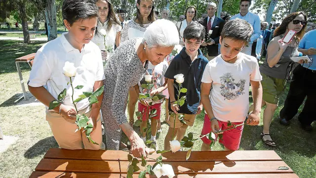 La viuda de Córdon y sus nietos colocan rosas blancas junto a la placa en honor al empresario, en el andador que lleva su nombre.