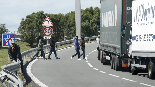 Inmigrantes cruzando la carretera cercana al Eurotúnel.