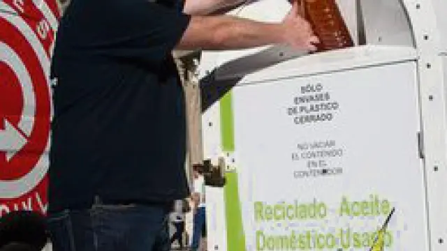 Un trabajador deposita una botella de aceite usado.