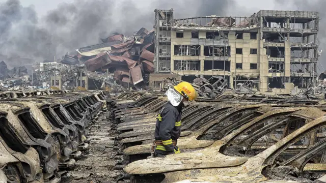 Un bombero camina sobre la zona afectada por la explosión en Tianjin