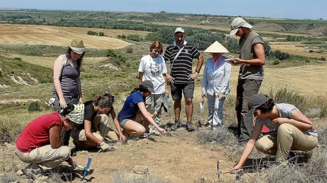 Alumnos y miembros del equipo de investigación en el yacimiento de Valletas, dentro del término municipal de Sena.