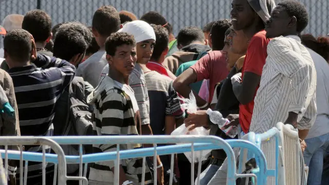 Los inmigrantes esperan tras llegar a la costa italiana.