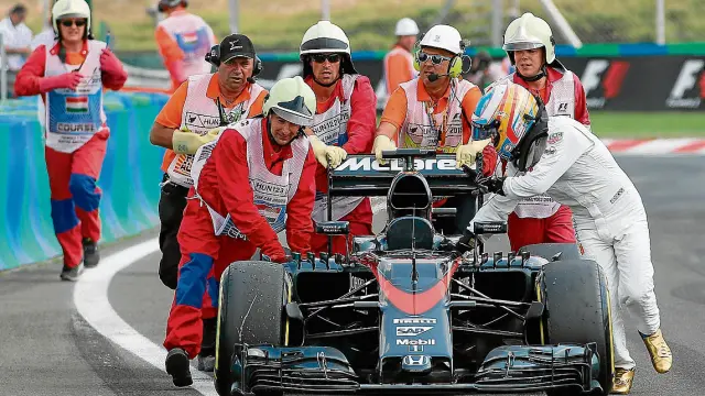 Alonso empuja su McLaren hacia los boxes ayudado por unos comisarios, ayer en la Q2.
