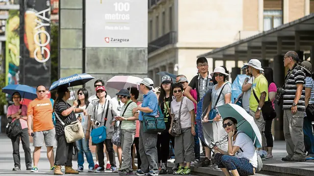 Un nutrido grupo de turistas asiáticos, junto a la oficina de Turismo de la plaza del Pilar.