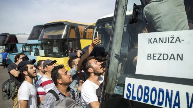 Refugiados tratan de coger un autobús con destino a la frontera con Croacia, este jueves en Horgos (Hungría).