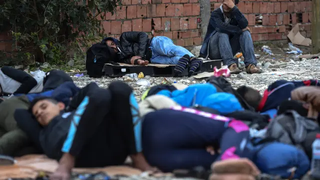 Varios inmigrantes descansan mientras esperan para recibir el permiso para coger un tren a la frontera con Serbia.