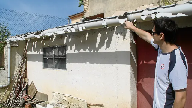 El concejal de Urbanismo y tesorero del Ayuntamiento de Torre del Compte, Miguel Burgués, muestra un canal de agua del tejado de una caseta de  huerta, que quedó destrozado después del inesperado granizo del pasado lunes.