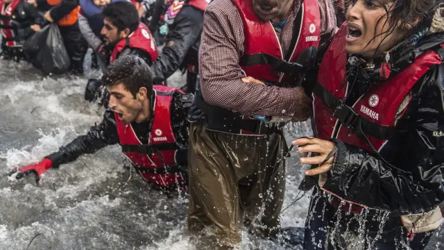Un grupo de personas desenbarcan en a costa de la isala griega de Lesbos desde Turquía.