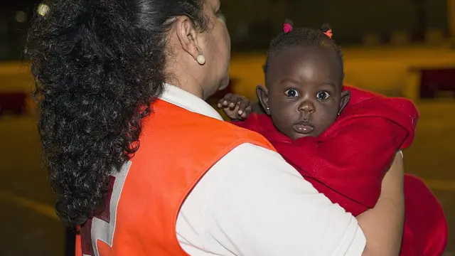 Una miembro de Cruz Roja atiende a un niño subsahariano que llegó en una de las pateras a la costa andaluza.
