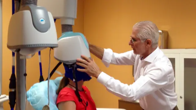 El neurocirujano aragonés Fernando Sanjuán coloca el casco de estimulación magnética transcraneal profunda a una paciente en la Unidad de Neuromodulación del Hospital La Milagrosa de Madrid.