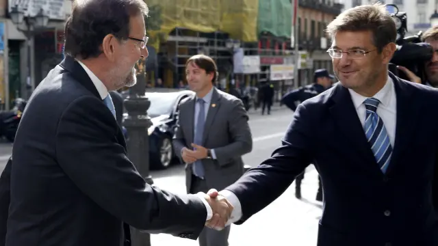 El presidente del Gobierno, Mariano Rajoy y el ministro de Justicia, Rafael Catalá, se saludan antes de la inauguración de la Oficina de Recuperación y Gestión de Activos.