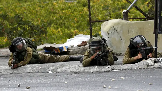 Soldados del ejército israelí toman posiciones durante un enfrentamiento con manifestantes palestinos en la ciudad cisjordana de Hebrón,