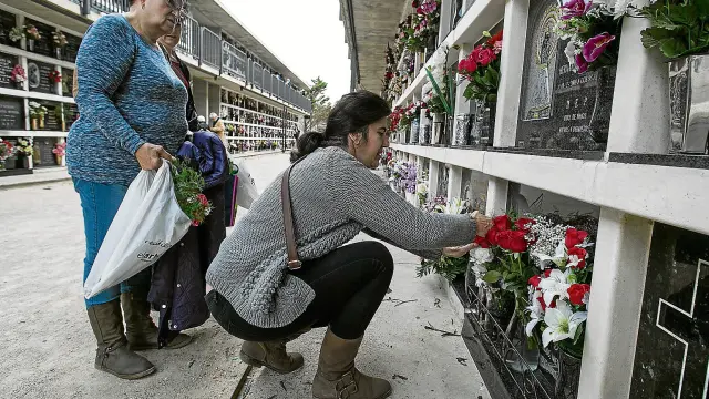 Teresa Lucía arregla las flores de un nicho en presencia de su madre, Celia Gómez, y su hermana Natalia, ayer, en Torrero.