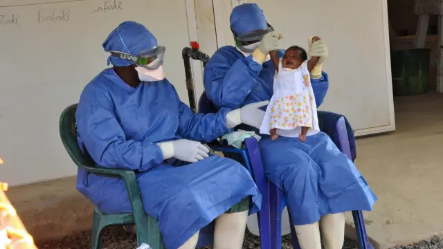 Trabajadores sanitarios de un centro de tratamiento en Conakry juegan con una niña infectada por el virus del ébola en Guinea.