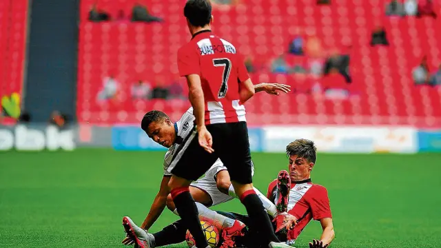 Etxeberría, en el suelo, y Guarrotxena, de espaldas, dos de los jóvenes titulares del Bilbao Athletic pugnan por el balón con Machís en la visita del Huesca a San Mamés que concluyó con empate a cero.