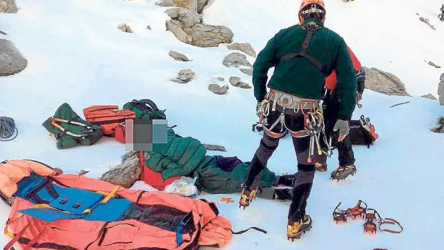 El montañero herido, tendido en el suelo, es atendido por un médico y un guardia de rescate.