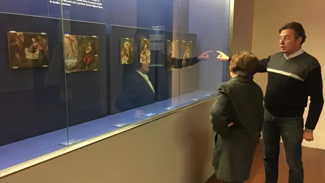 Un voluntario de los amigos del Museo enseña a una visitante los dos nuevos crismones.