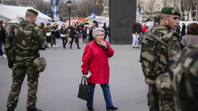 Una mujer camina junto a dos soldados franceses.