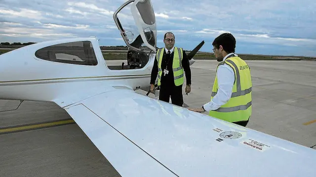 El jefe de vuelo de la escuela de formación de pilotos Atlantic Flight Airways Aviation, Pedro Ortiz (al fondo), revisa la avioneta antes de iniciar una sesión práctica de instrucción nocturna en el aeropuerto Huesca-Pirineos