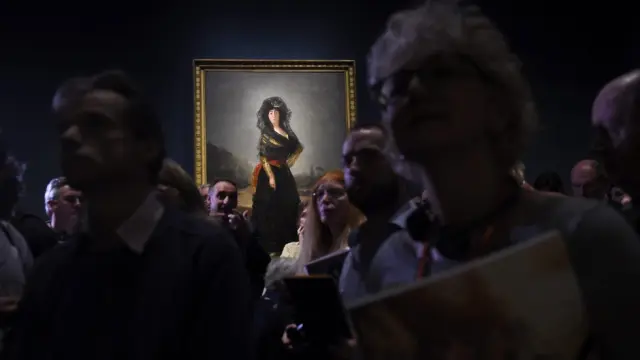 Visitantes de la exposición de retratos de Goya en la National Gallery de Londres, con el cuadro de la Duquesa de Alba de luto al fondo.