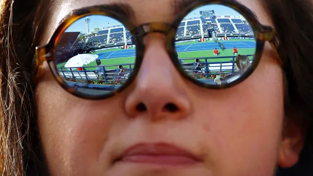 Una joven con gafas en un partido de tenis.