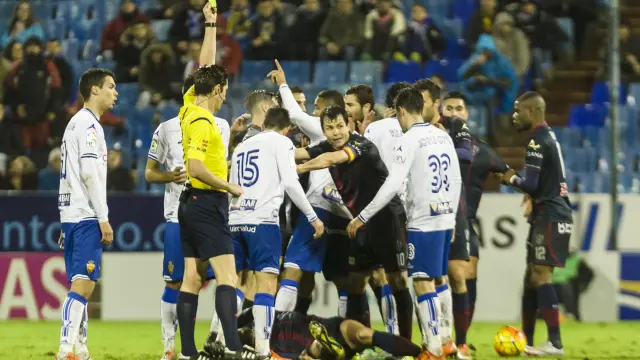El árbitro muestra una tarjeta amarilla múltiple en una discusión entre jugadores del Real Zaragoza y el Huesca.