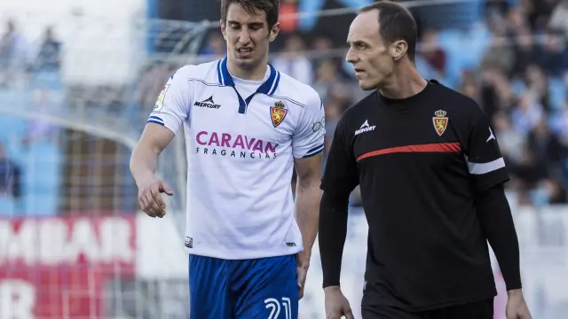 Momento en el que Joan Campins abandona el campo lesionado, acompañado del fisioterapeuta Míchel Román, en el partido ante el Girona del pasado domingo.