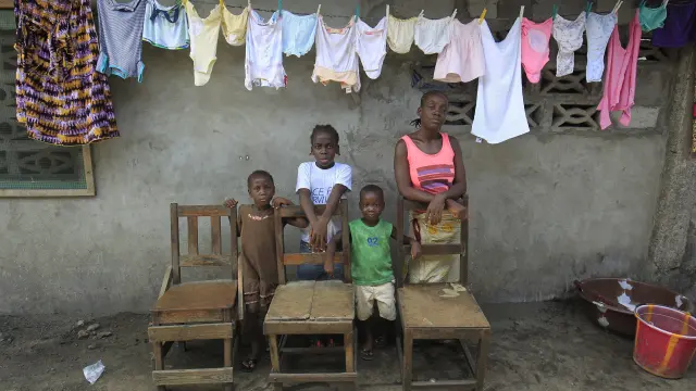 Victoria Topay (d) y sus hijos posan junto a sillas vacías que simbolizan a su marido y otros familiares fallecidos víctimas del ébola en Monrovia.