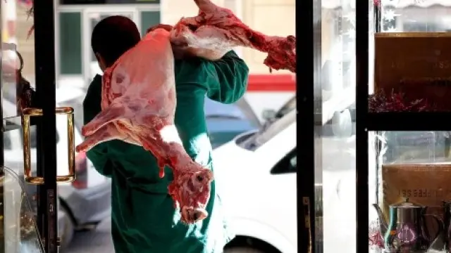 Un carnicero transporta un cordero sacrificado orientado a la Meca