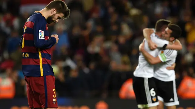 El defensa, Gerard Piqué, se lamenta mientras los jugadores del Valencia celebran la victoria.