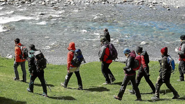 Un grupo de voluntarios, guiados por un forestal, inicia la búsqueda por las orillas del río.