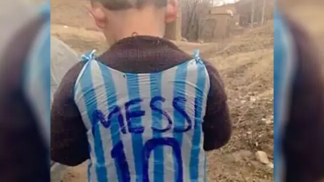 El niño afgano Murtaza muestra la camiseta de Messi de plástico.